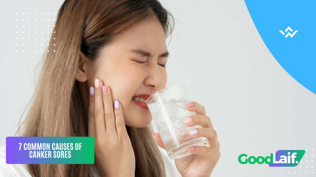 Woman in pain holding her cheek while drinking water, illustrating common causes of canker sores
