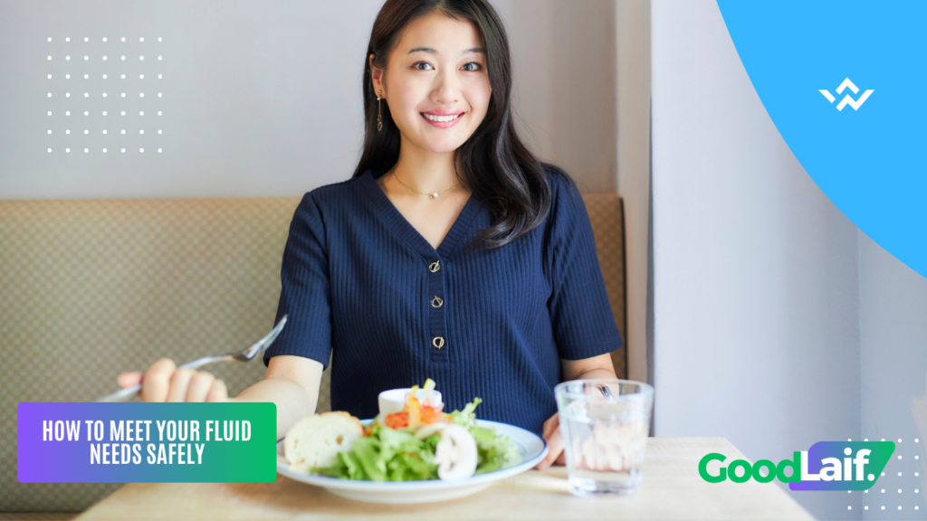 Woman smiling at a table with food and water, illustration of how to meet fluid needs wisely to avoid the risks of drinking too much water and hyponatremia
