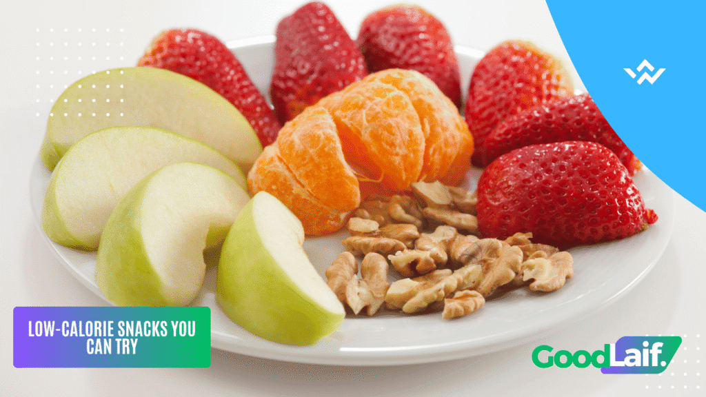 Plate with sliced apple, strawberries, orange and nuts as examples of low-calorie snacks
