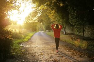 Woman walking on a sunlit autumn path, a gentle habit for menopause bloating belly